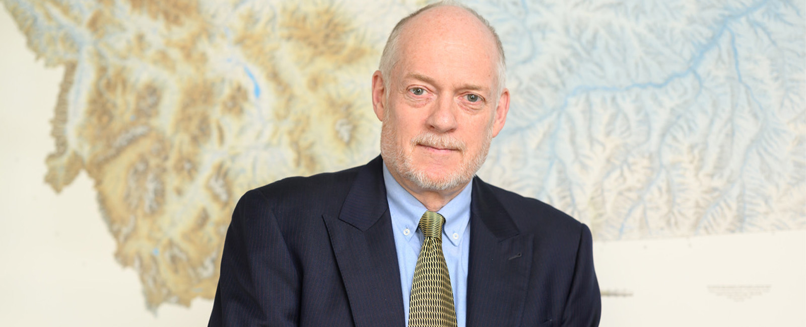 Professor Tim Swager smiles in front of a map.