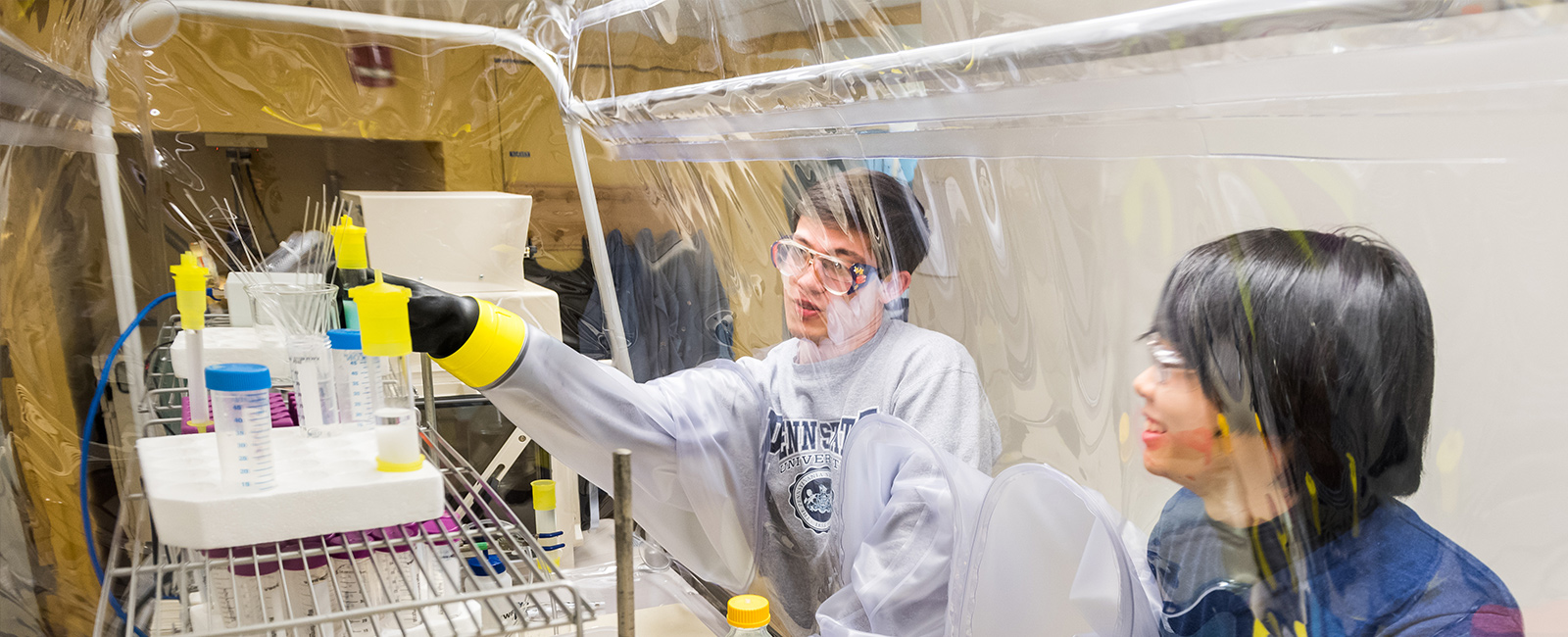 Two graduate students conduct research at a fume hood.