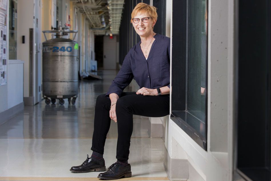 Professor Laura Kiessling perches on a windowsill in a hallway.