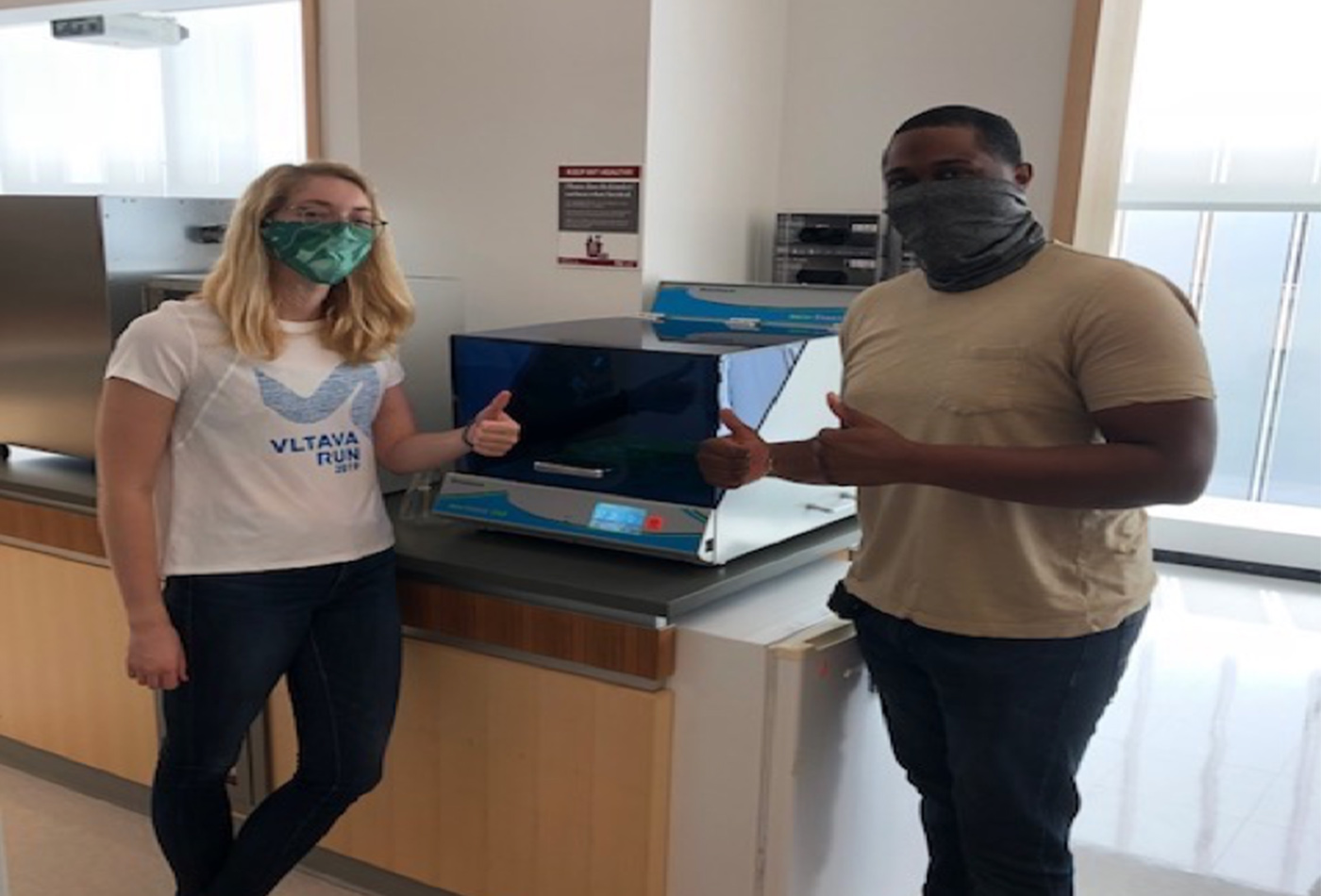 Two teaching assistants pose with a new piece of lab equipment.