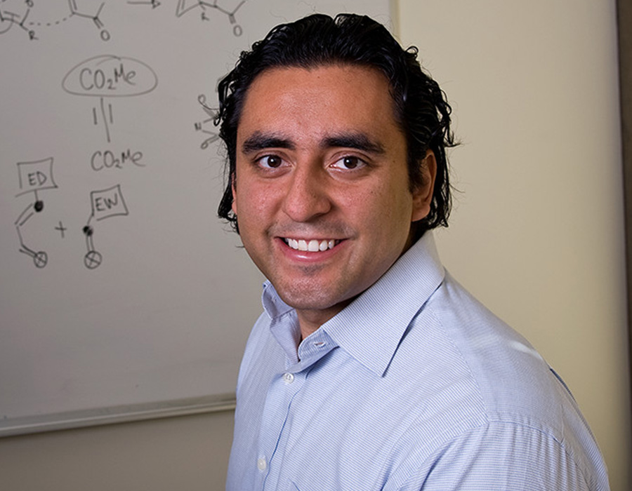 Yuriy Román smiles in front of a white board.