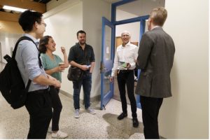 Moungi Bawendi talks and laughs with three faculty members outside a classroom.