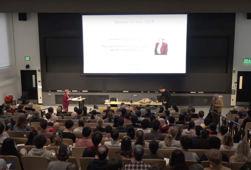 JoAnne Stubbe stands before a packed lecture hall delivering her lecture.