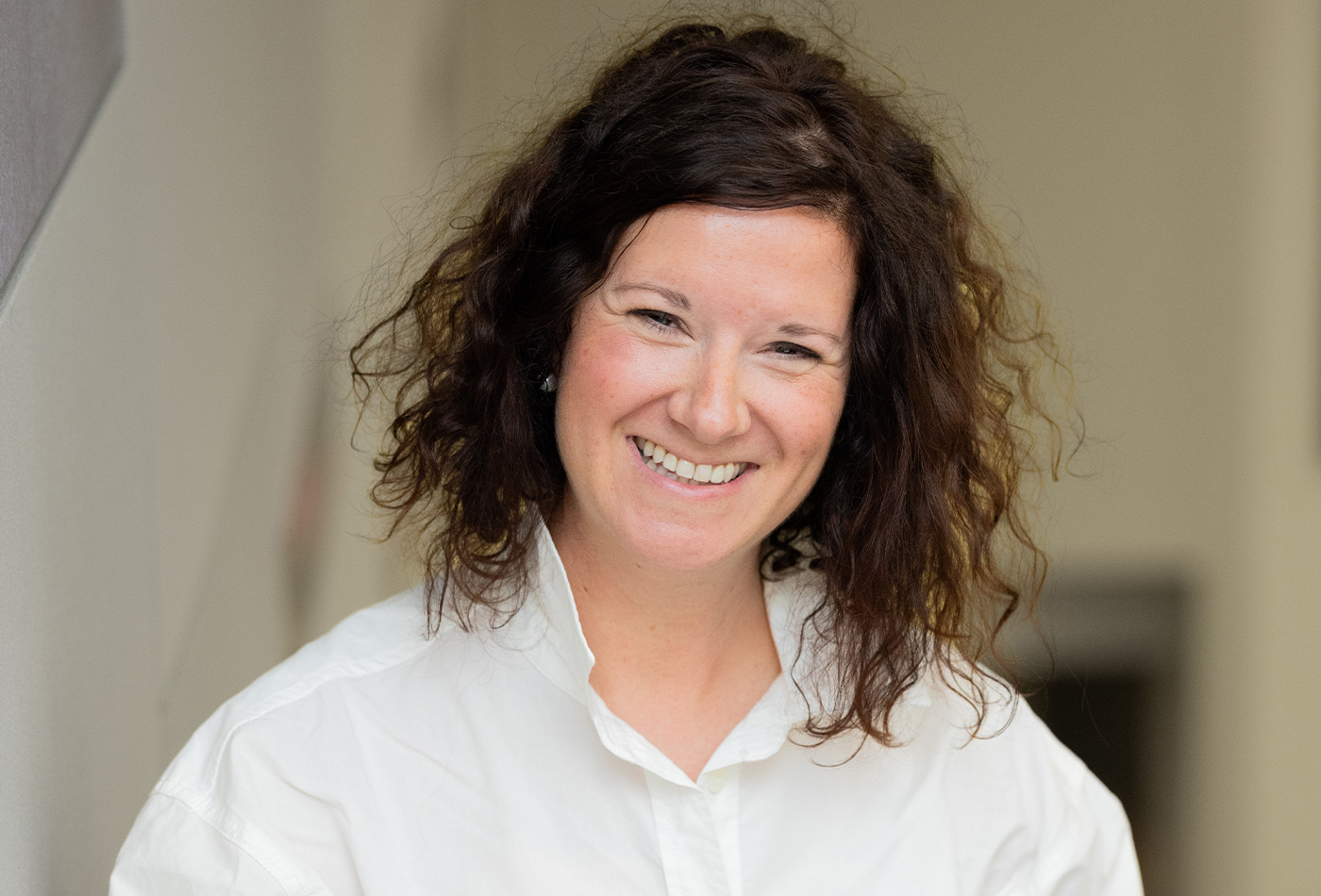 Corrie Lefebvre smiles in a lecture hall wearing a white oxford shirt and a black skirt.