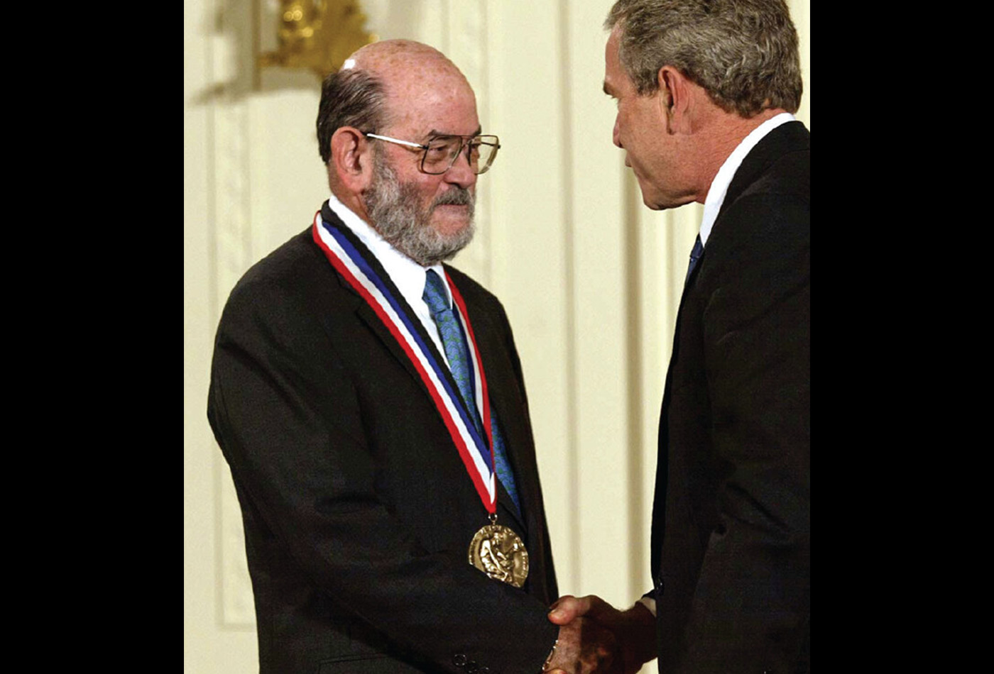 John Brauman wears a National Medal of Science around his neck as he shakes the hand of President George W. Bush.